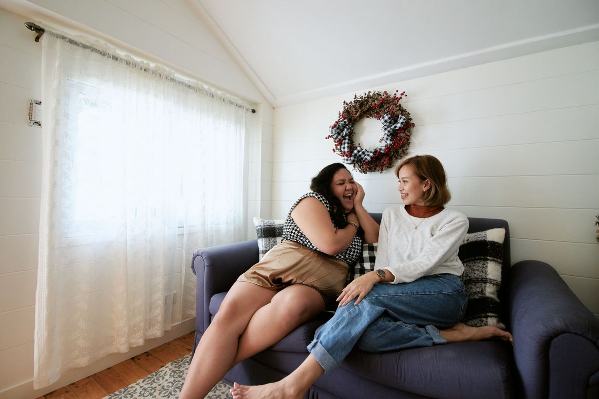 Bad breath Kharghar: two friends laughing and talking up close on a sofa in a bright room