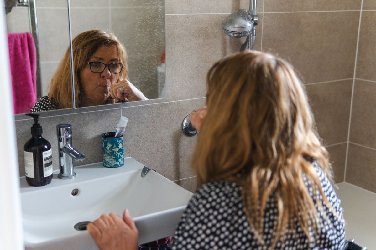 Bleeding gums when brushing Kharghar: woman brushing her teeth at a bathroom mirror