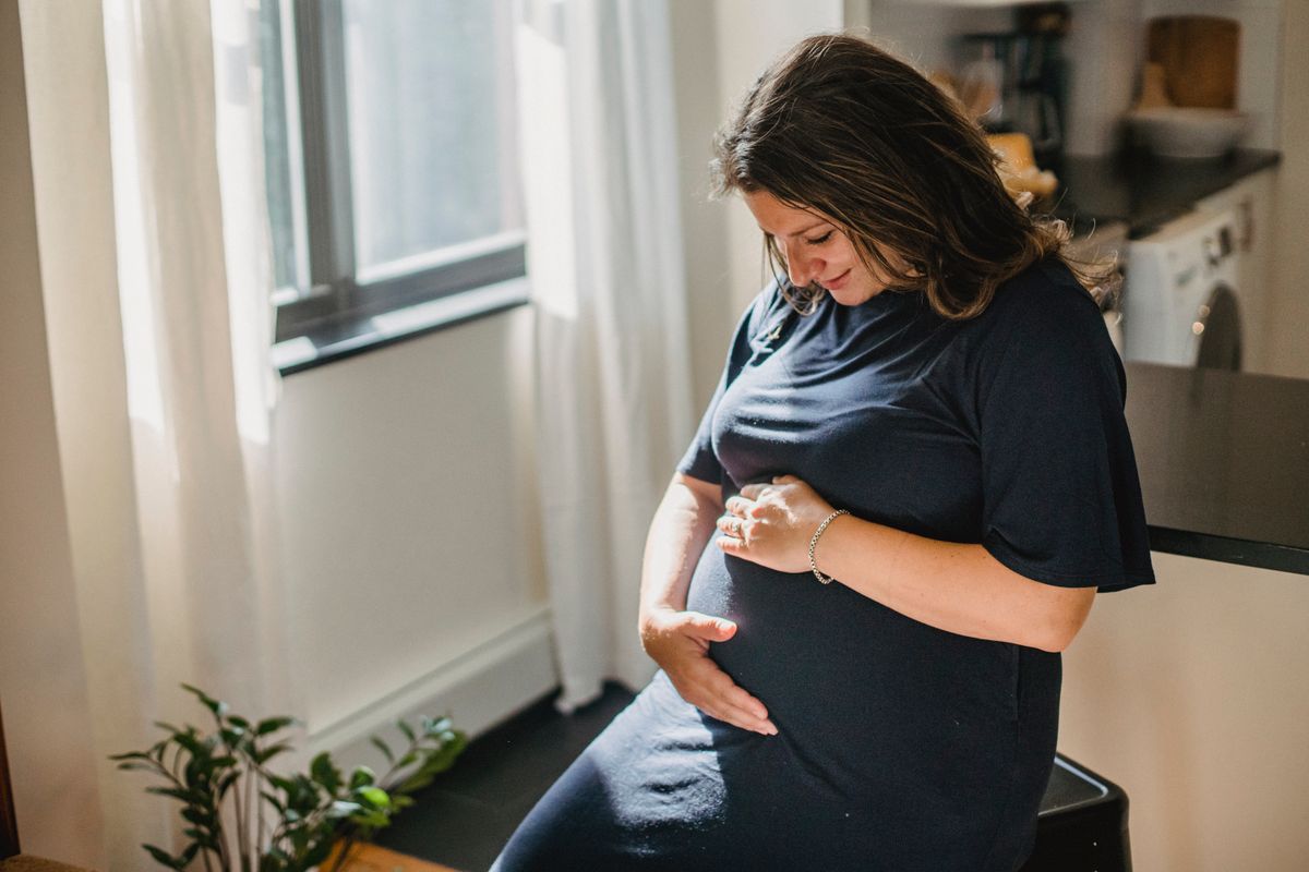 Dental care during pregnancy Kharghar: pregnant woman resting hands on her belly in warm natural light at home