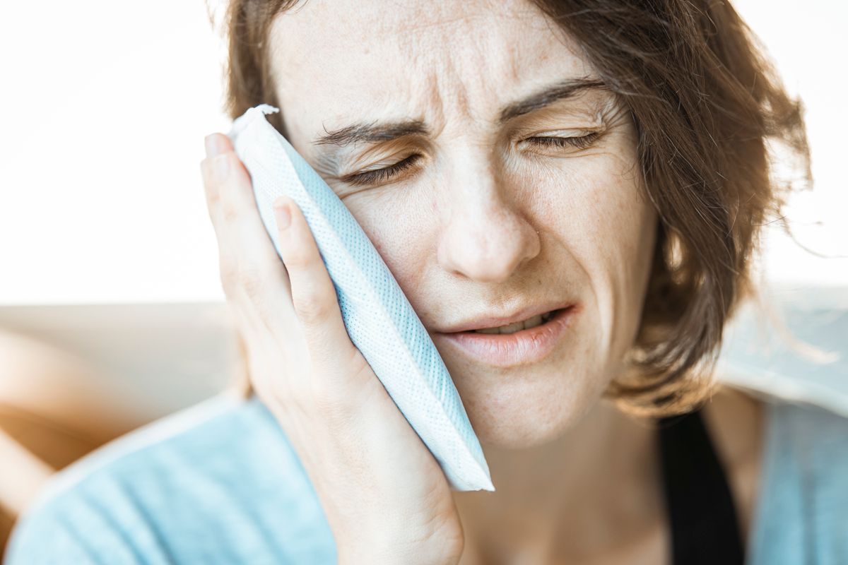 Dental emergency in Kharghar: a woman holding a cold compress to her cheek to ease toothache at home