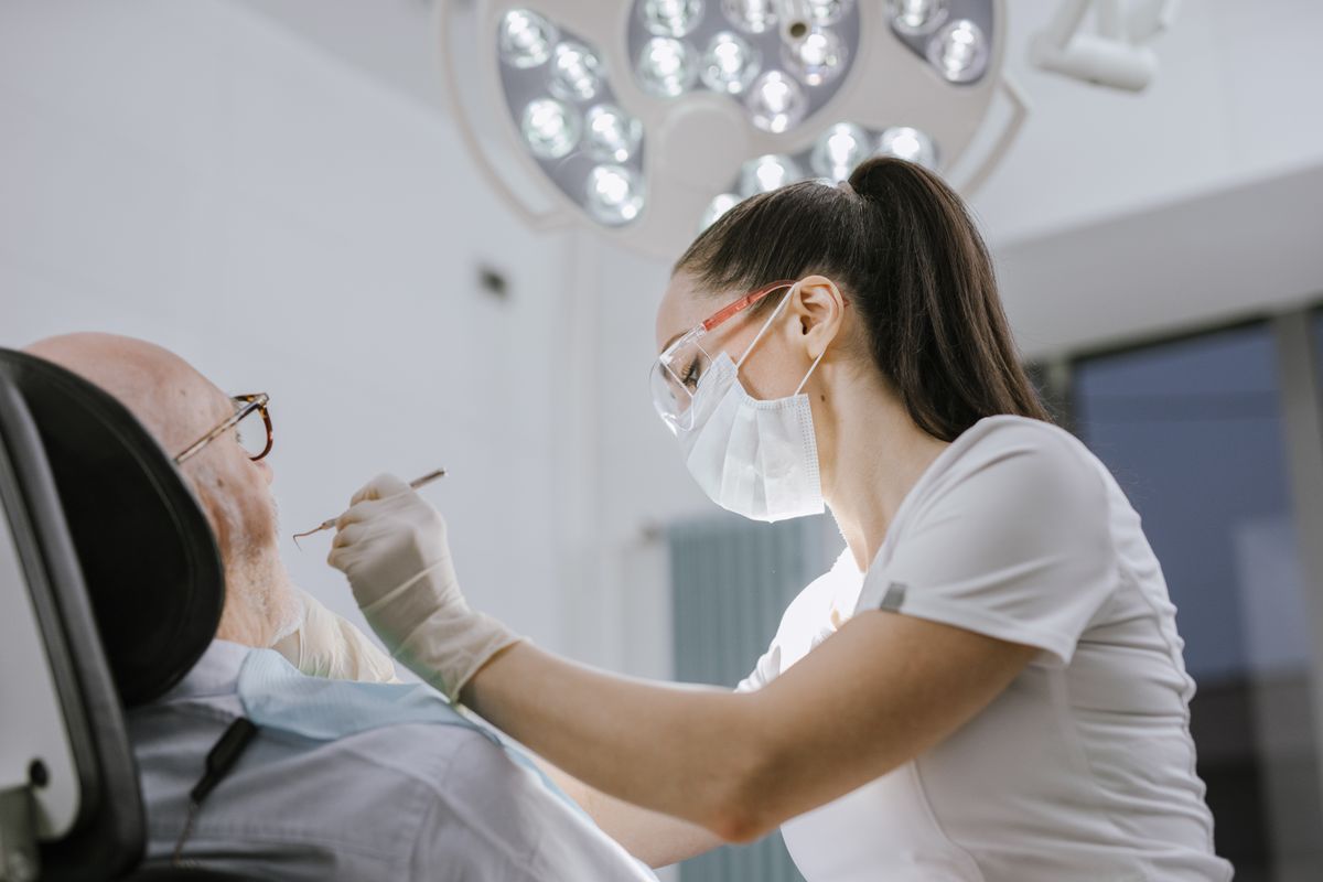 Dentist examining a patient's teeth under bright clinic lighting