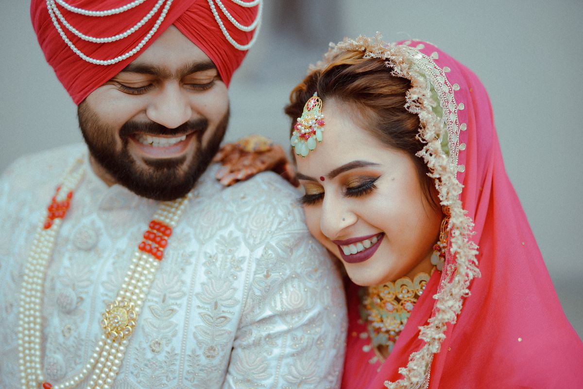 A joyful Indian bride and groom smiling in traditional wedding attire